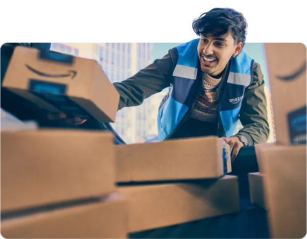 A man in a blue Amazon vest reaches into the open trunk of a vehicle with half a dozen packages and grabs one package.