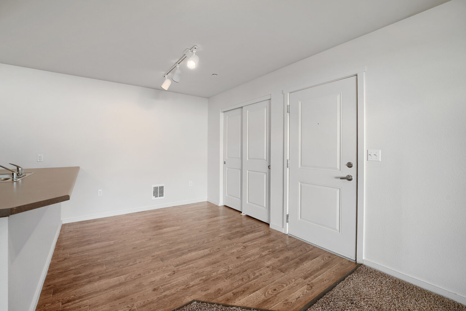 Open dining area with wood-style flooring, breakfast bar, and entryway at Copper Hill Apartments in Spokane Valley, WA