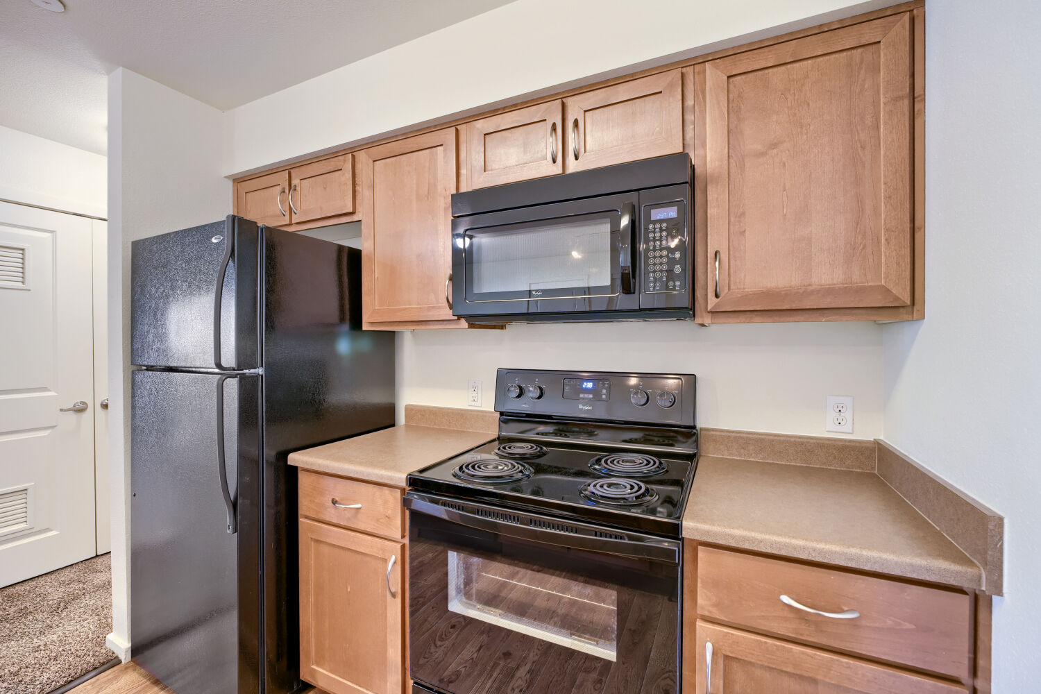 Well-appointed kitchen featuring black appliances, wood cabinetry, microwave, and generous countertop space at Copper Hill Apartments in Spokane Valley, WA