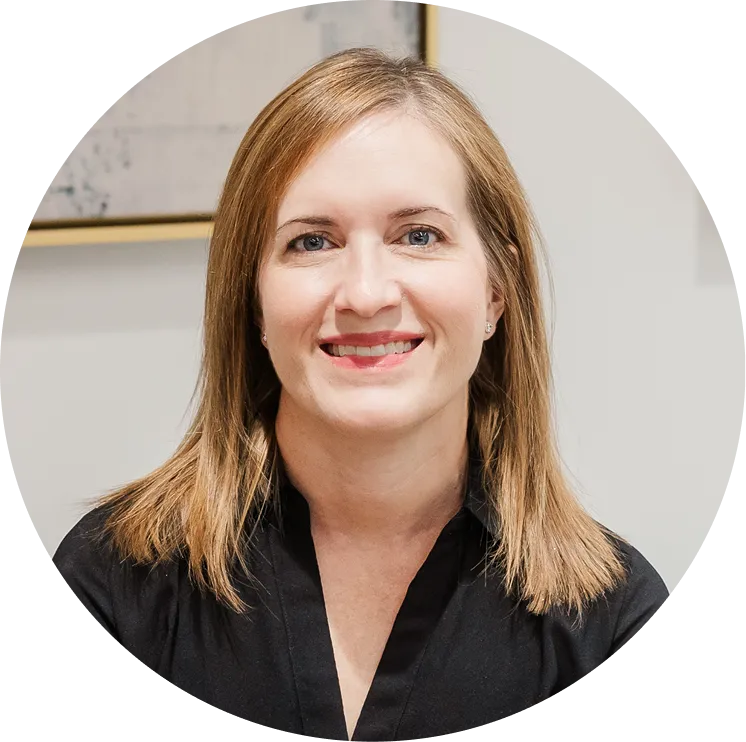 Smiling woman with light brown hair wearing a black top against a light background.