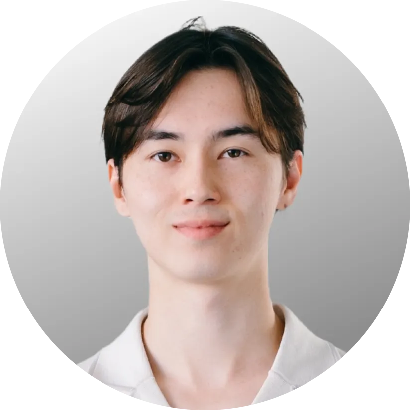 Porträt eines jungen Asian-Mannes mit kurzen braunen Haaren und hellem Hemd vor grauem Hintergrund.