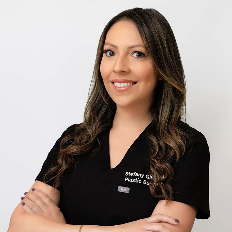 Smiling woman with long brown hair in black scrubs with name and title embroidered on shirt