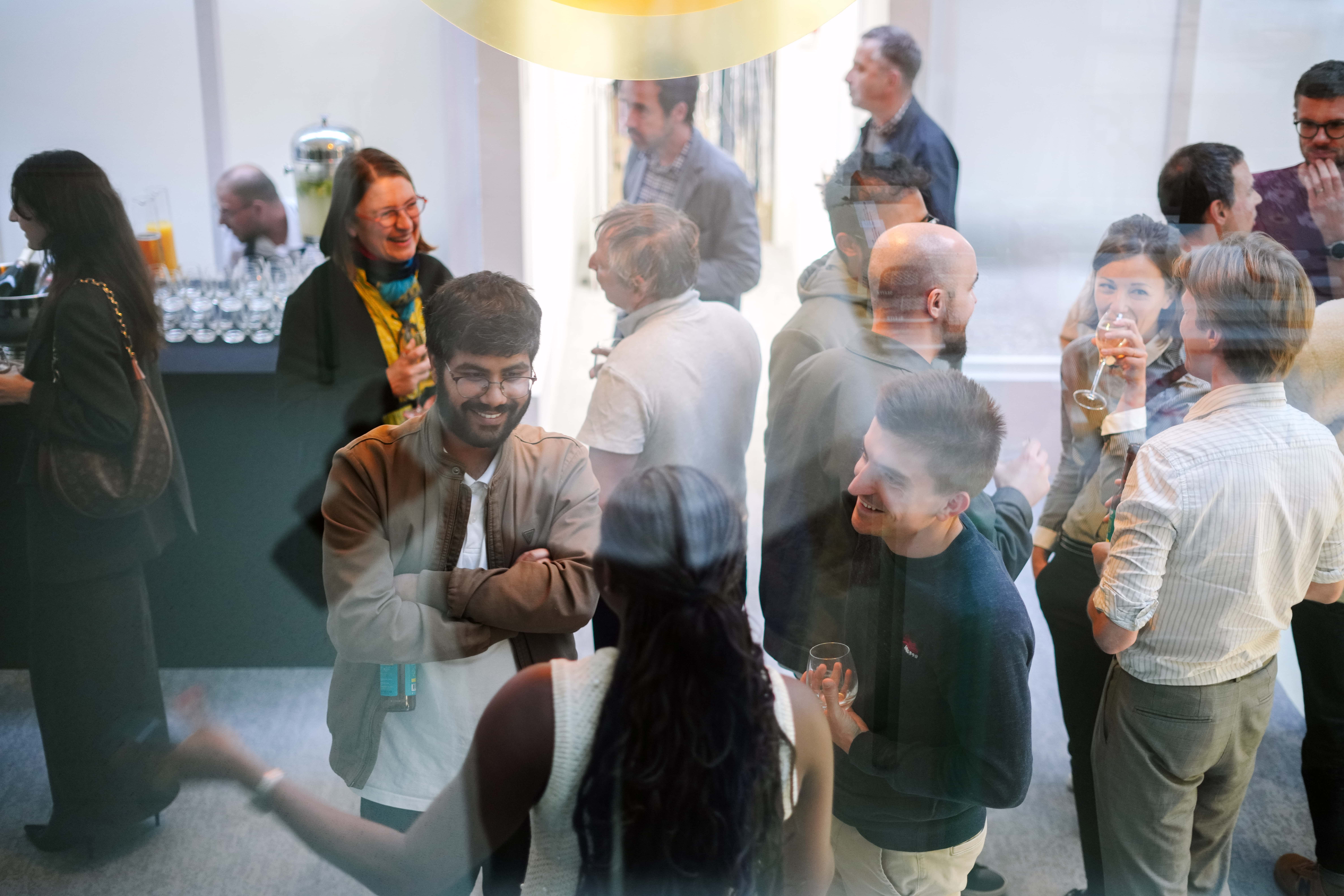 A group of people socializing and smiling at a casual indoor gathering.