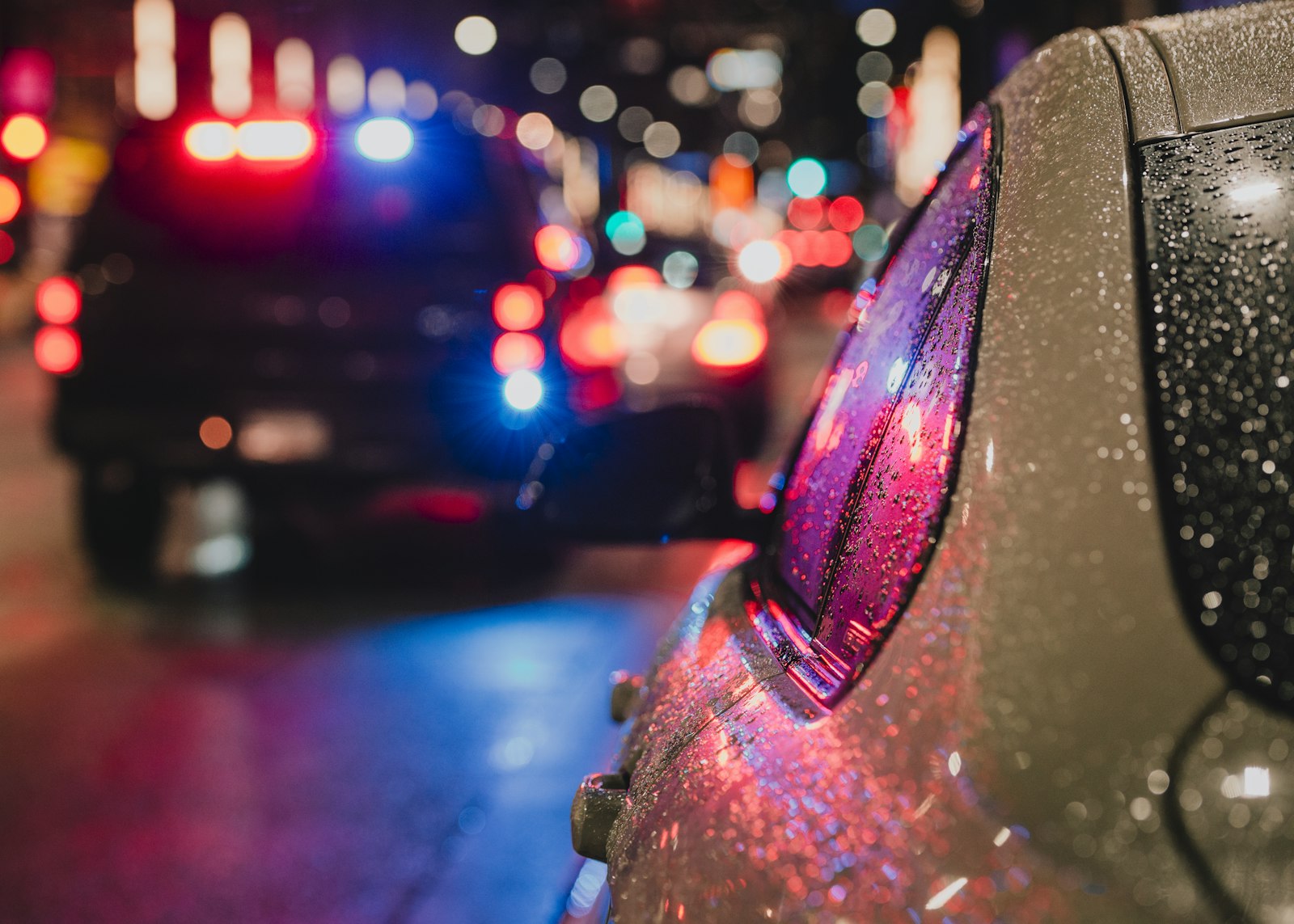 Police lights reflecting on a wet car at night after a hit and run accident in Florida