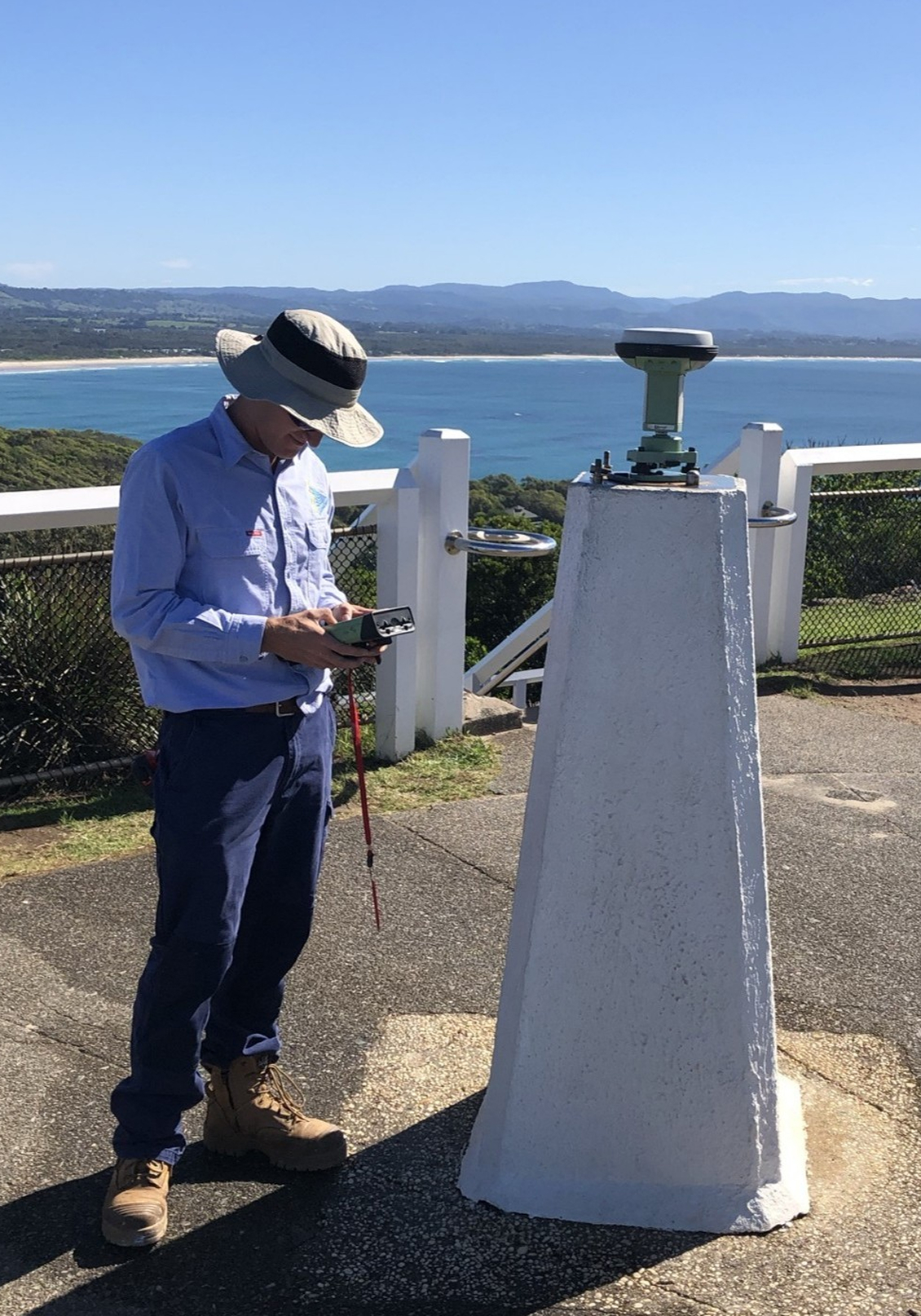 Land surveyor standing at a geodetic monument completing static GNSS campaign