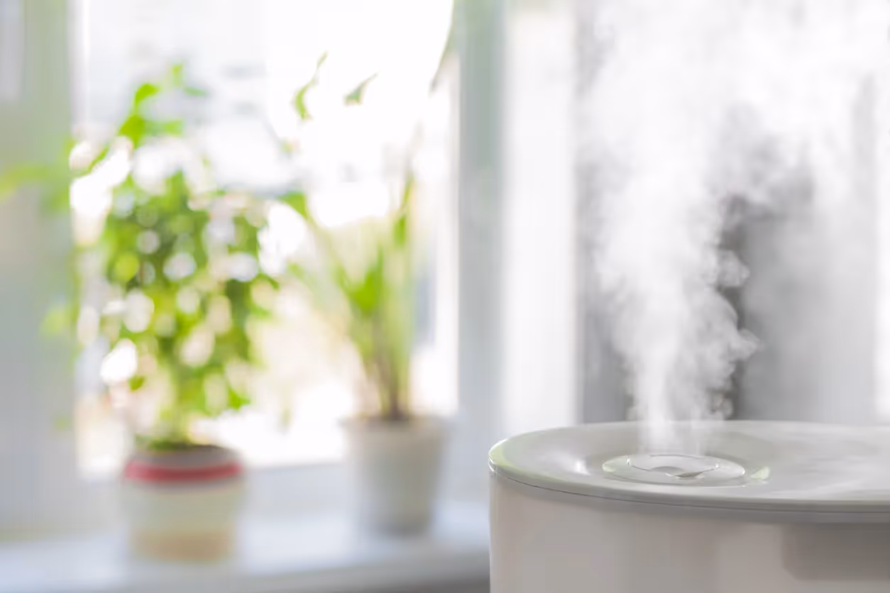 A close-up of a humidifier releasing mist in a bedroom