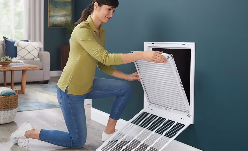 Woman inserting filter into wall vent.