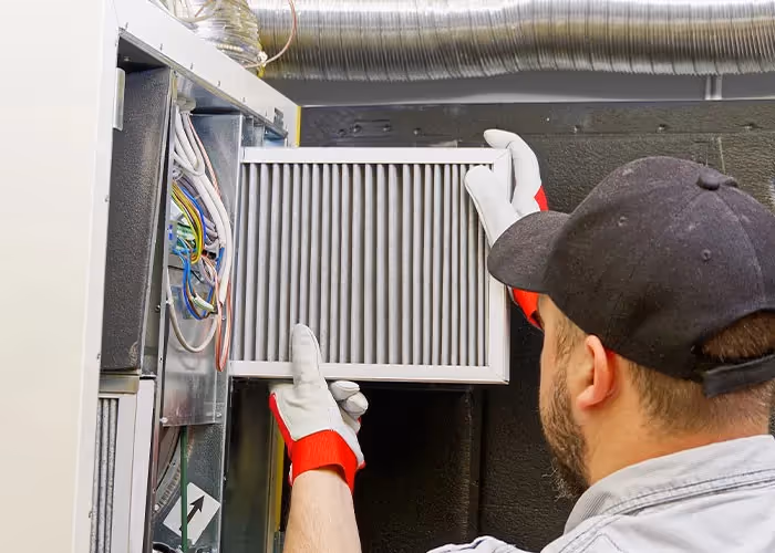 Technician inserting new HVAC air filter.