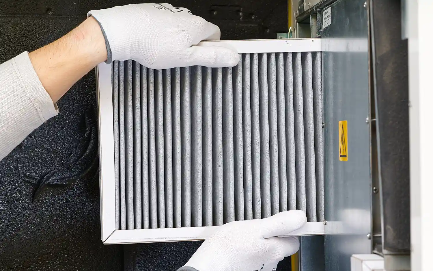 Gloved hands placing clean HVAC filter.
