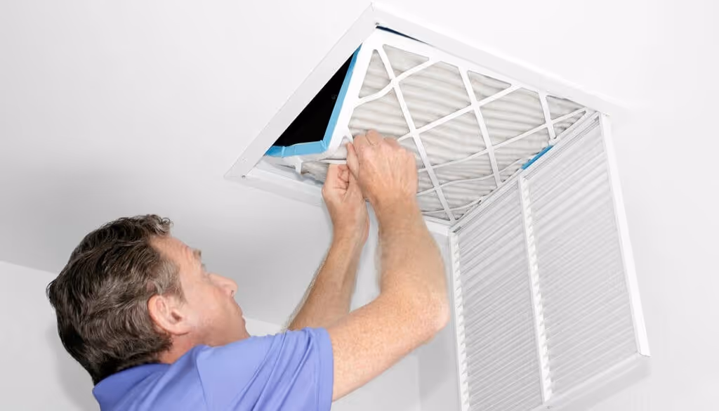 Man installing air filter into ceiling.