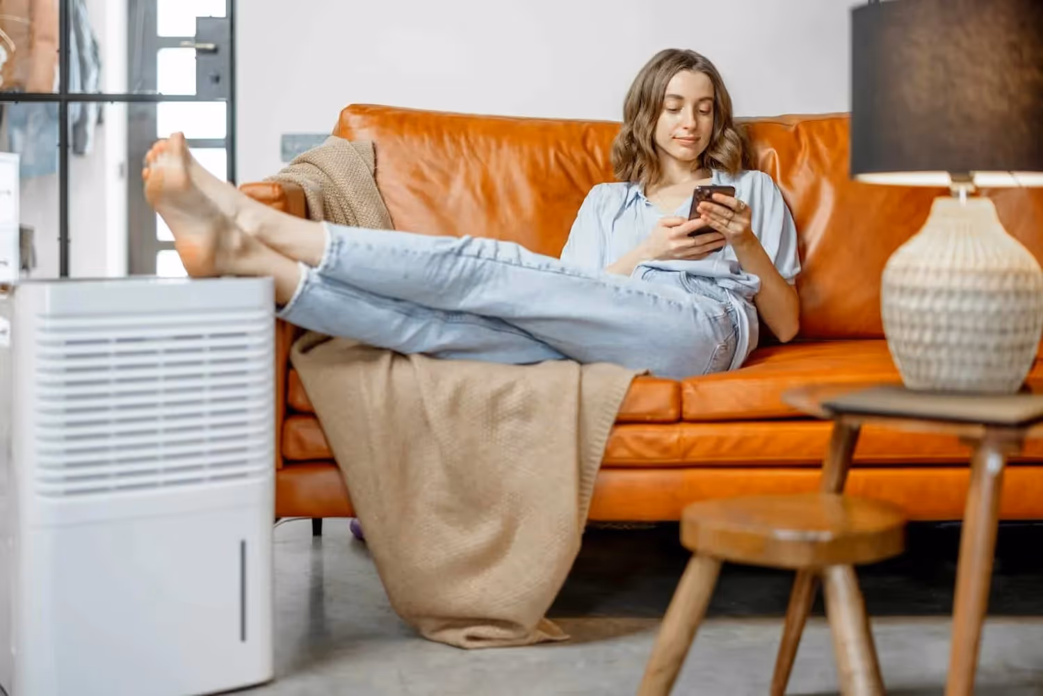 Woman using phone near white dehumidifier.