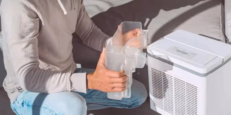 Man emptying water tank from dehumidifier.