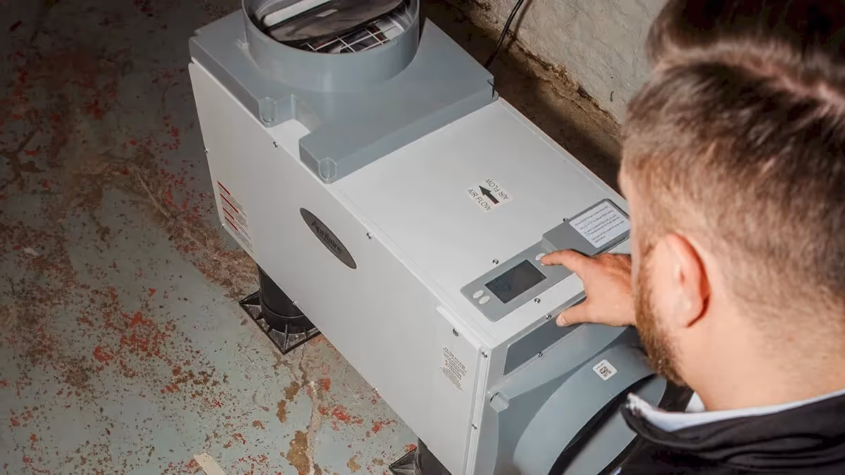 Man pressing buttons on dehumidifier controls.