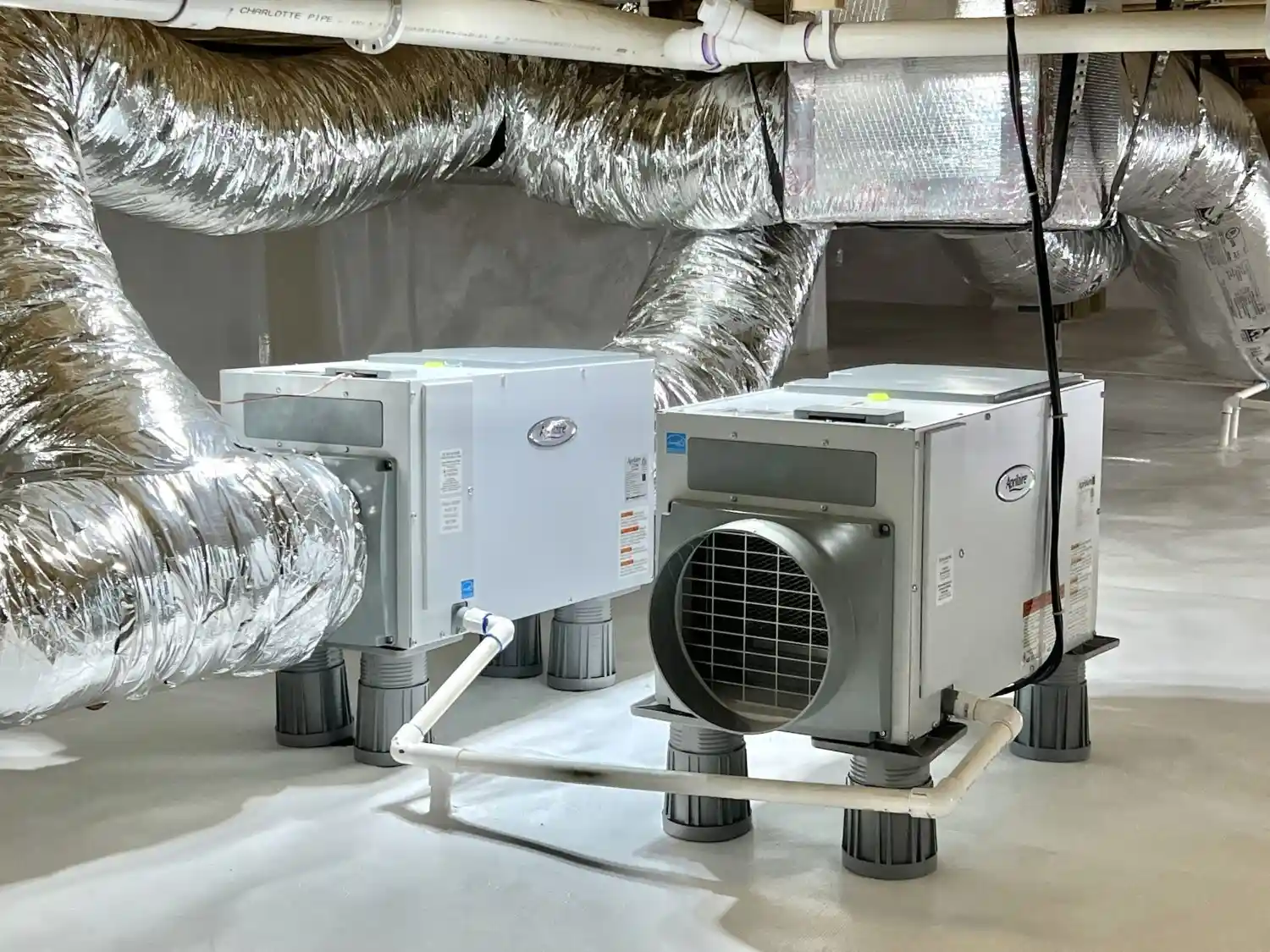 Technician installing dehumidifier in low crawlspace.