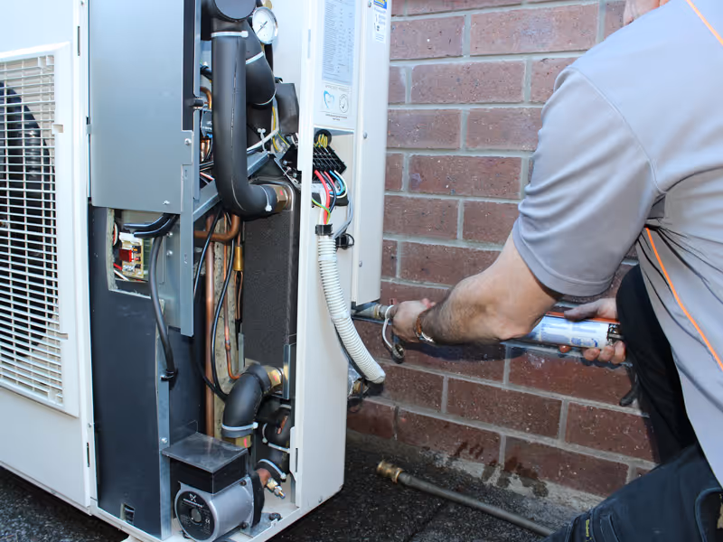 HVAC technician performing maintenance on a heat pump system