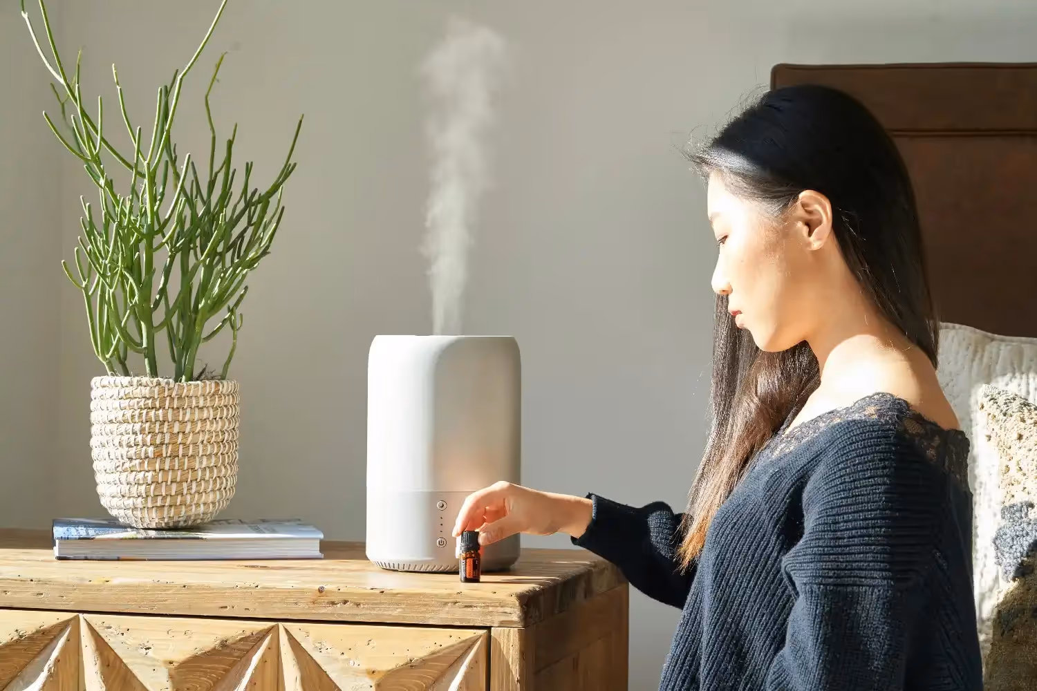 Woman adding oil to white humidifier.