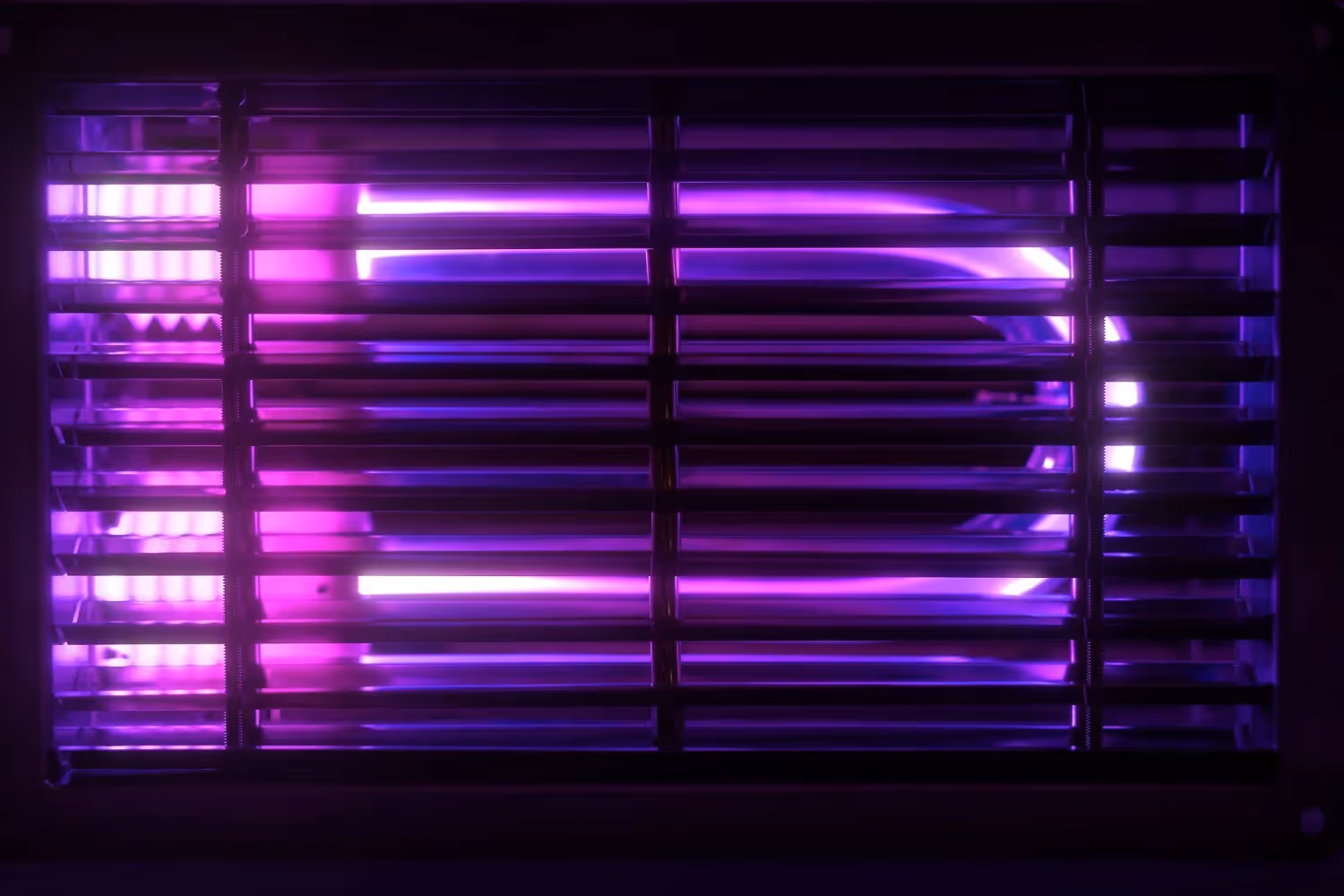 Close-up of UV light device glowing purple-pink behind a protective grill, used for sanitation or pest control.