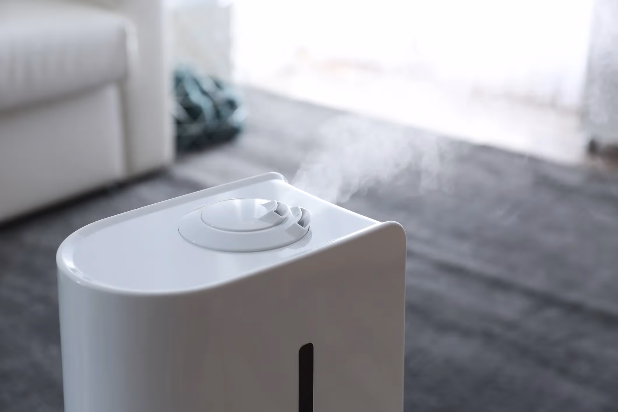 A close-up of a humidifier releasing mist in a bedroom