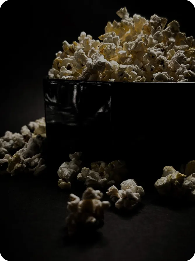 попкорн у чорній посудині, знятий у студійному освітленні на темному фоні