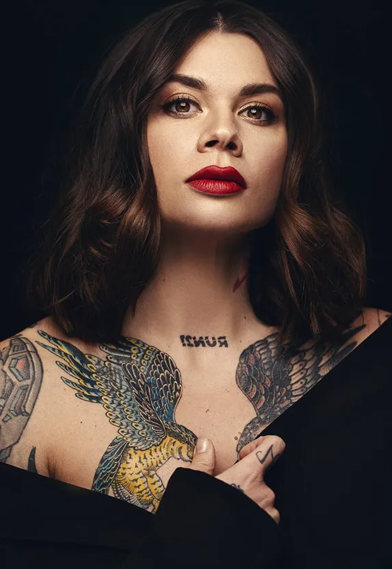Студійний портрет жінки з яскравим макіяжем і татуюванням на руці, знятий у професійному світлі. Фото демонструє атмосферу сучасної комерційної зйомки та високий рівень роботи зі світлом і композицією.