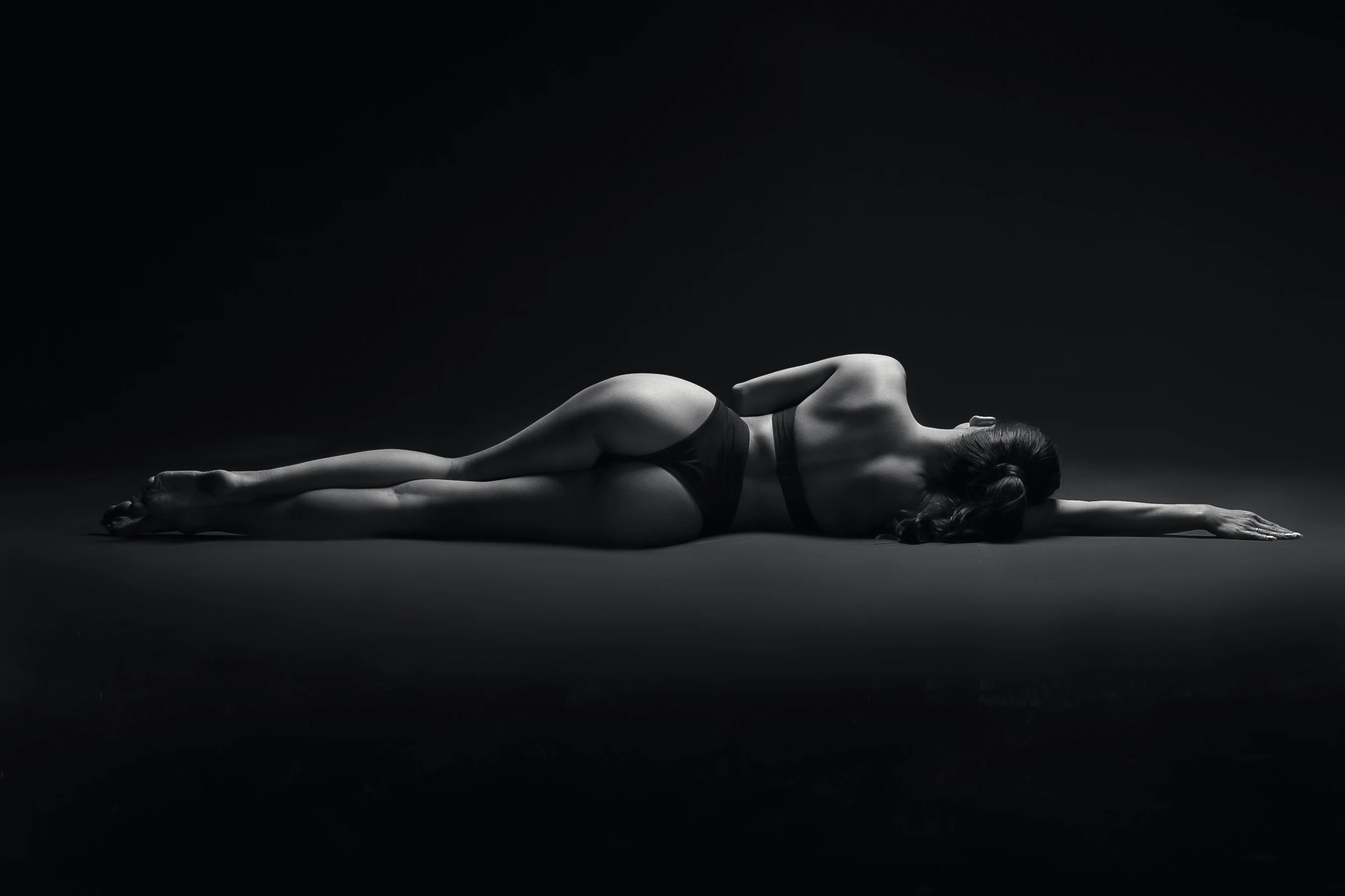 Студійне чорно-біле фото, дівчина лежить на підлозі в нижній білизні