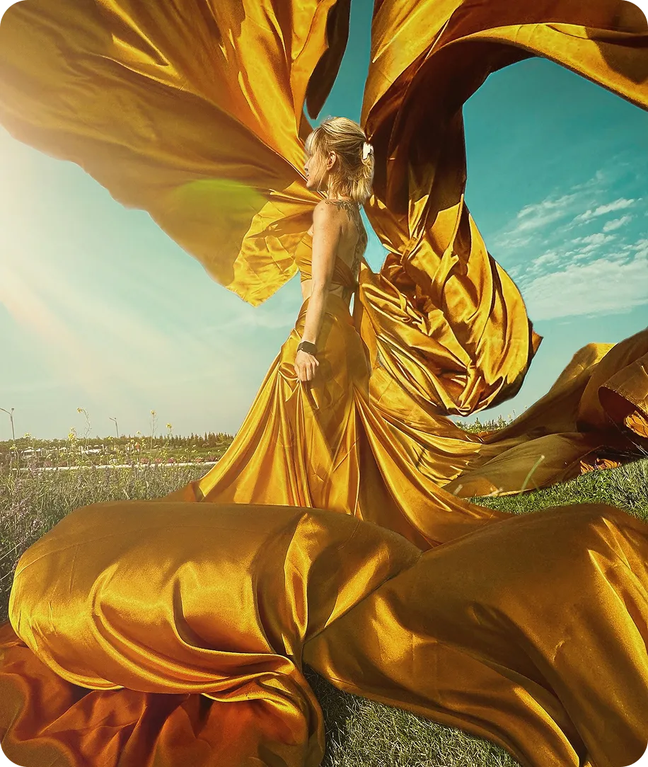 Дівчина на фоні природи в жовтому платті, яке розлітається ефектно вітром