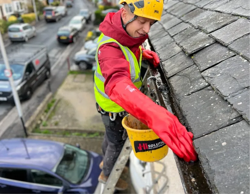 A roofing technician cleaning gutters