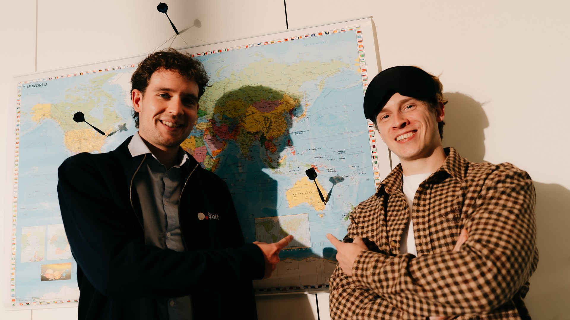 Sander Crijns and Arnoud Dekeyzer of Spott pointing at Australia on a world map with darts