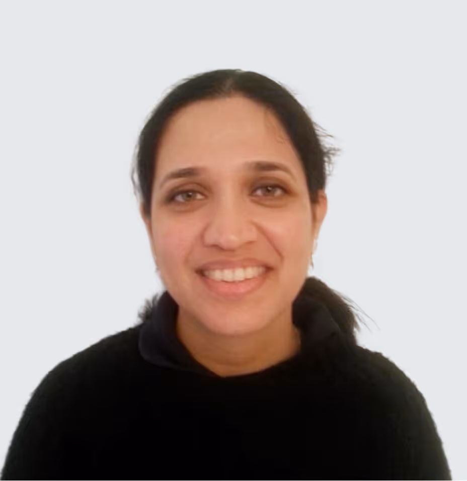 Portrait of a smiling woman with dark hair tied back wearing a black sweater.