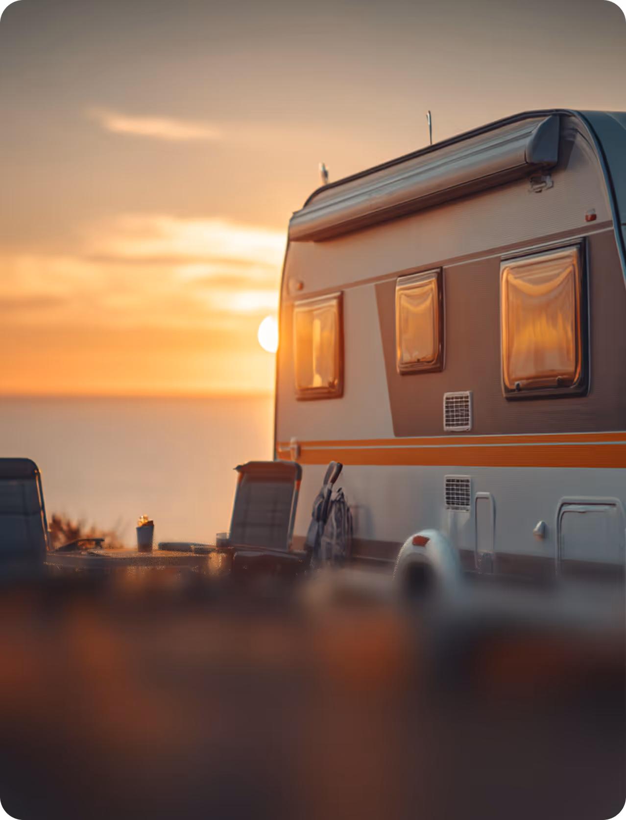 Campingvogn og stole ved solnedgang udendørs ved vandet.
