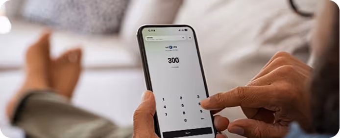 Person entering the number 300 on a smartphone calculator app while reclining on a couch.