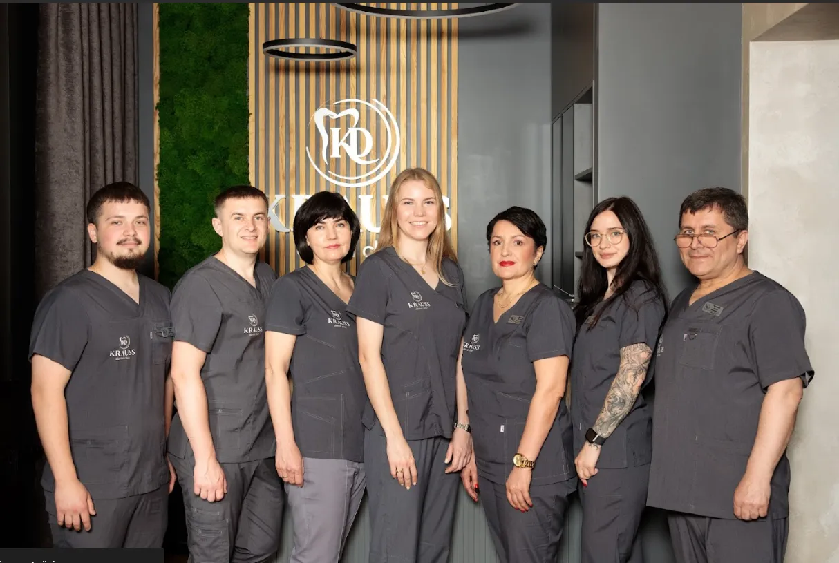 Group of seven healthcare professionals in gray scrubs standing indoors, smiling at the camera.
