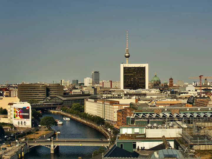 Blick auf Berlins Innenstadt mit Spree, Fernsehturm und historischen Gebäuden bei klarem Himmel.