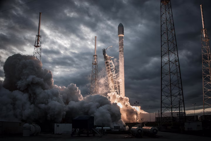 Raketenstart bei bewölktem Himmel mit viel Rauch und Flammen am Boden.