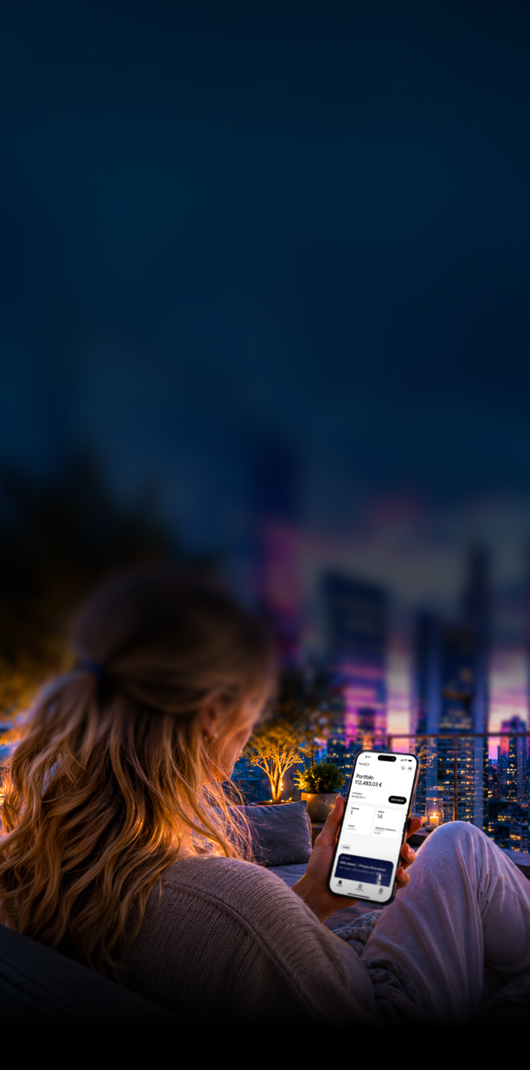 Frau sitzt abends auf Terrasse und sieht auf Smartphone ihr Portfolio mit 112.483,03 € vor Skyline.