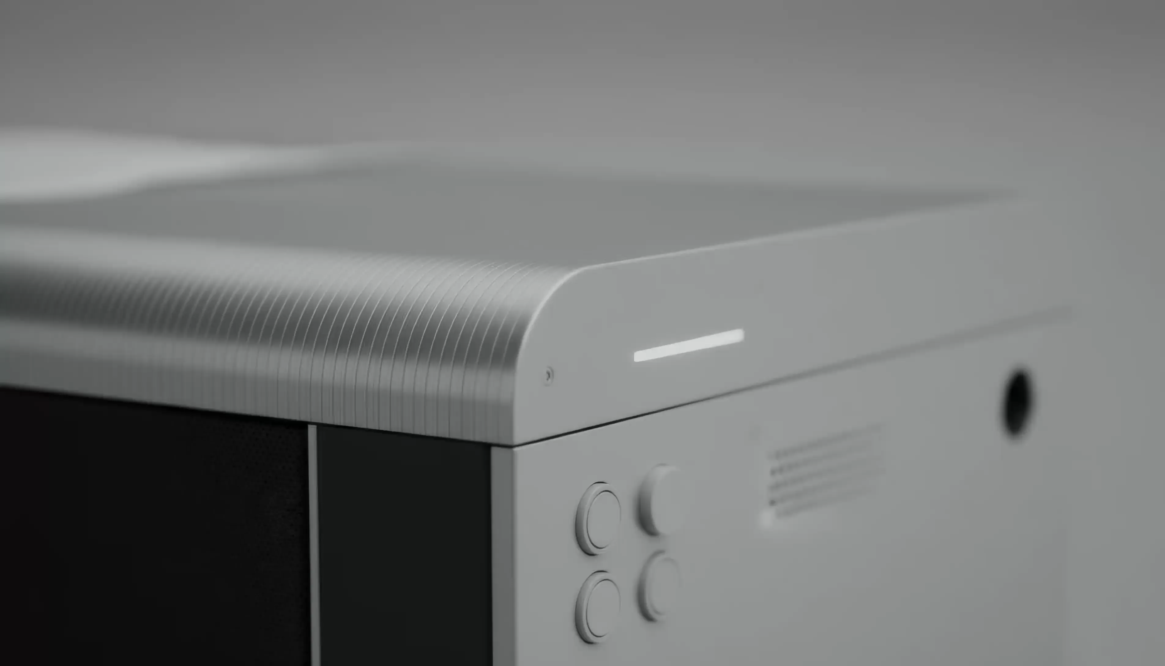 Close-up of a sleek, modern electronic device corner with rounded top edge, illuminated horizontal indicator light, and four circular control buttons.