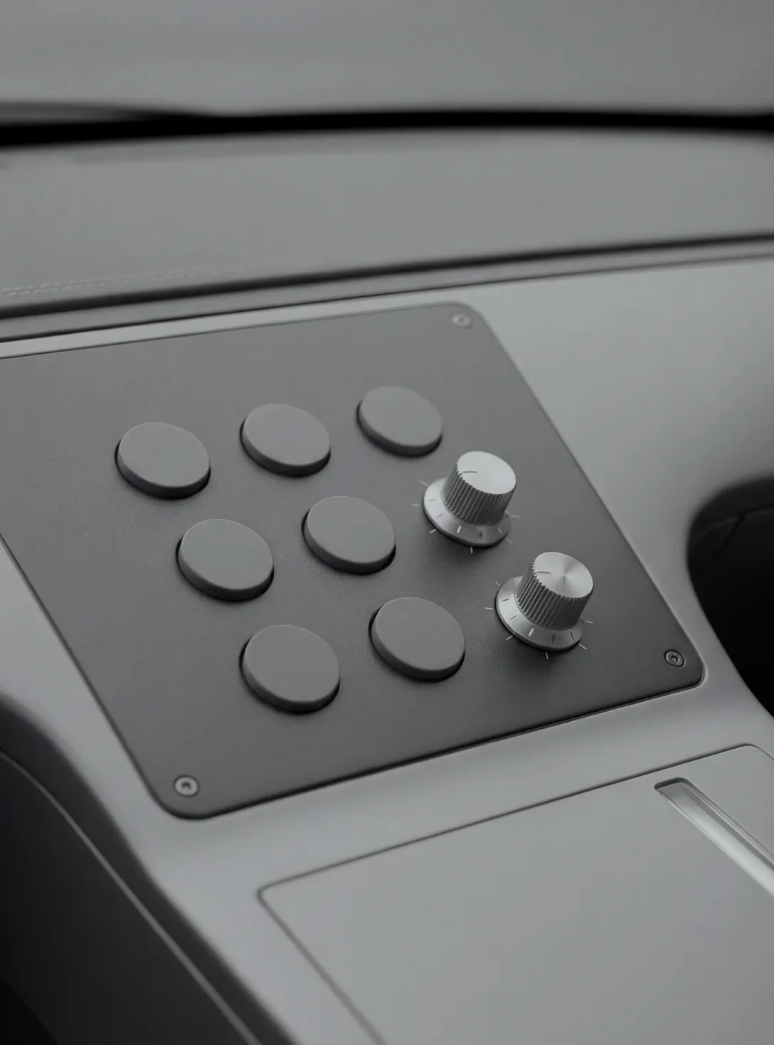 Close-up of a control panel with seven round buttons and two metal rotary knobs on a matte surface.