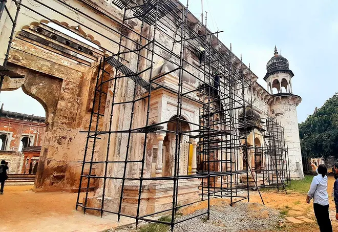Old historic building undergoing restoration with scaffolding around it and people nearby.