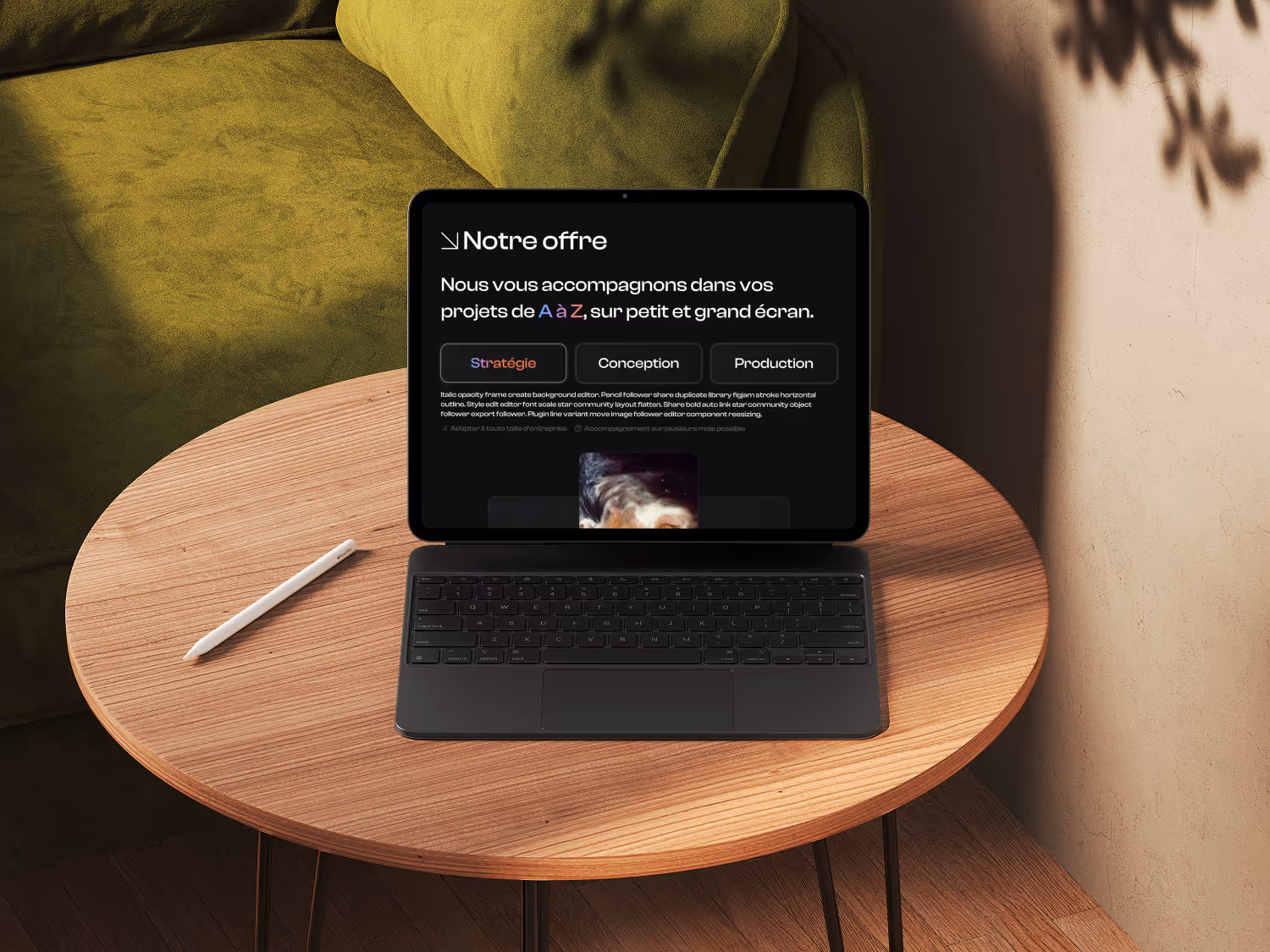 Tablet with keyboard and digital pen on wooden round table, screen showing Scob website on about page.