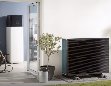 Unité de pompe à chaleur extérieure noire à côté d'une porte vitrée ouverte avec une plante en pot et une arrosoir sur le sol.