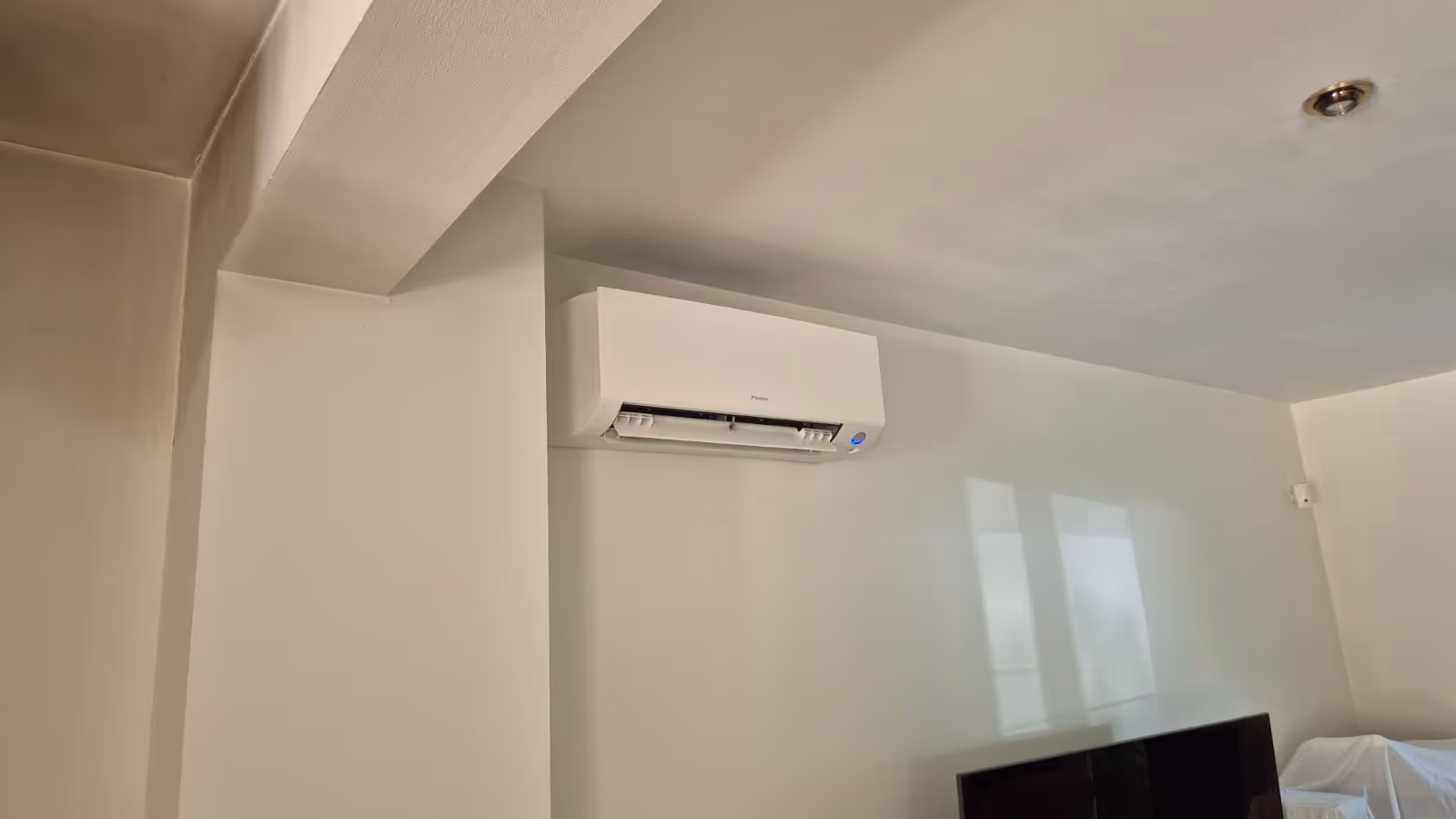 Un climatiseur mural Daikin installé sur un mur blanc dans une pièce moderne.