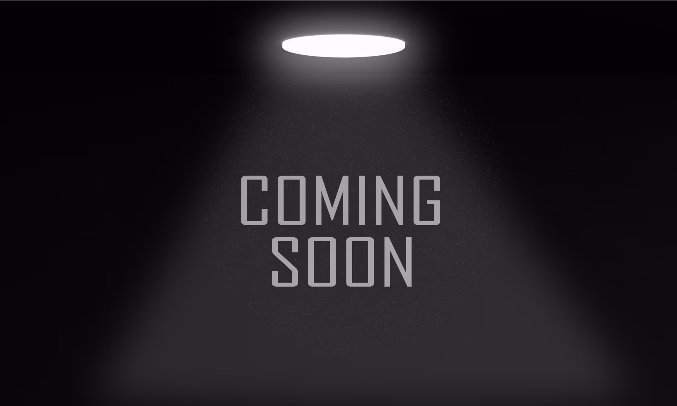Spotlight shining from above on the text 'COMING SOON' against a dark background.