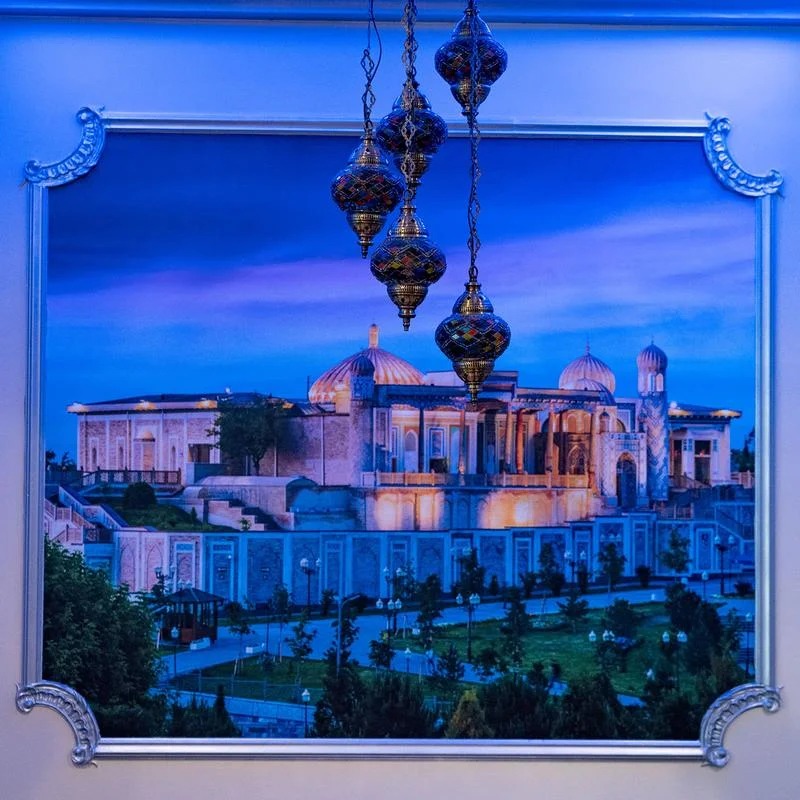 A painting of a building with a blue sky and hanging ornaments.