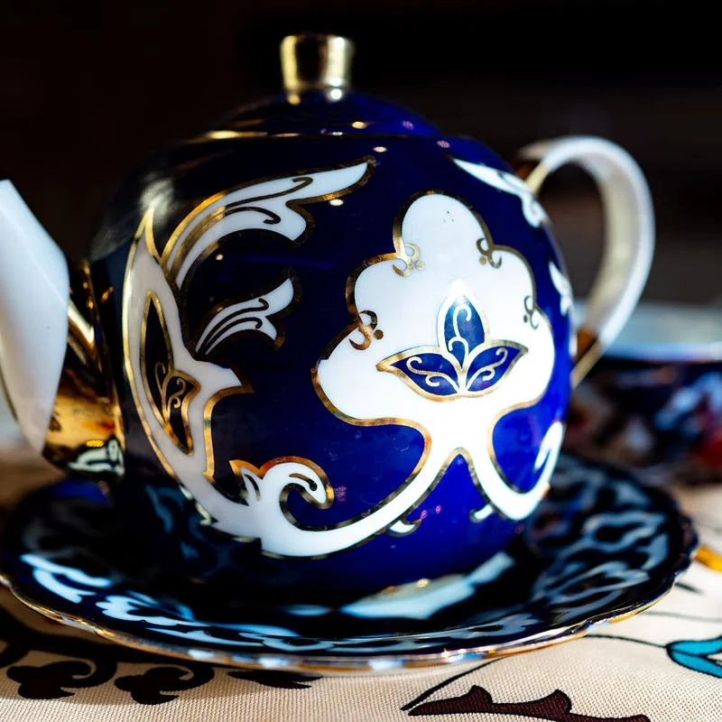 A blue and white teapot with a gold spout and handle.