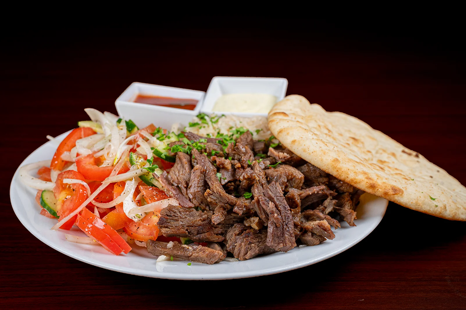 A plate of food with a meat dish and a bread roll.