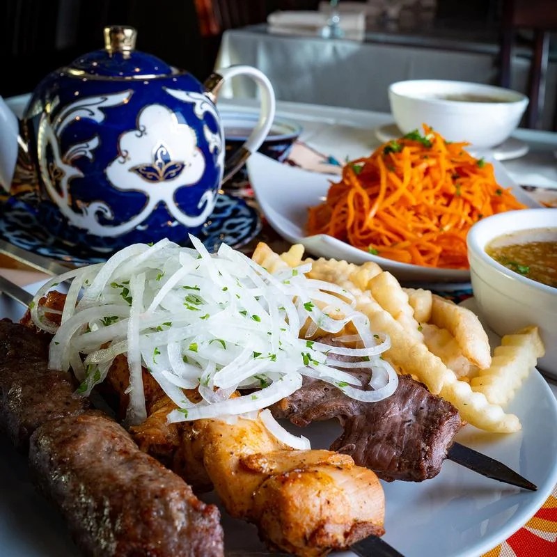 A plate of food featuring meat, sautéed onions, and crispy fries arranged appetizingly.