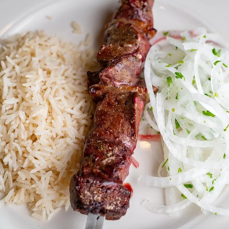 A plate of rice and meat with a side salad.