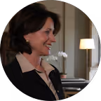 Lächelnde Frau mit kurzen dunklen Haaren in einem eleganten schwarzen Outfit vor einem weißen Hintergrund mit einer Lampe.