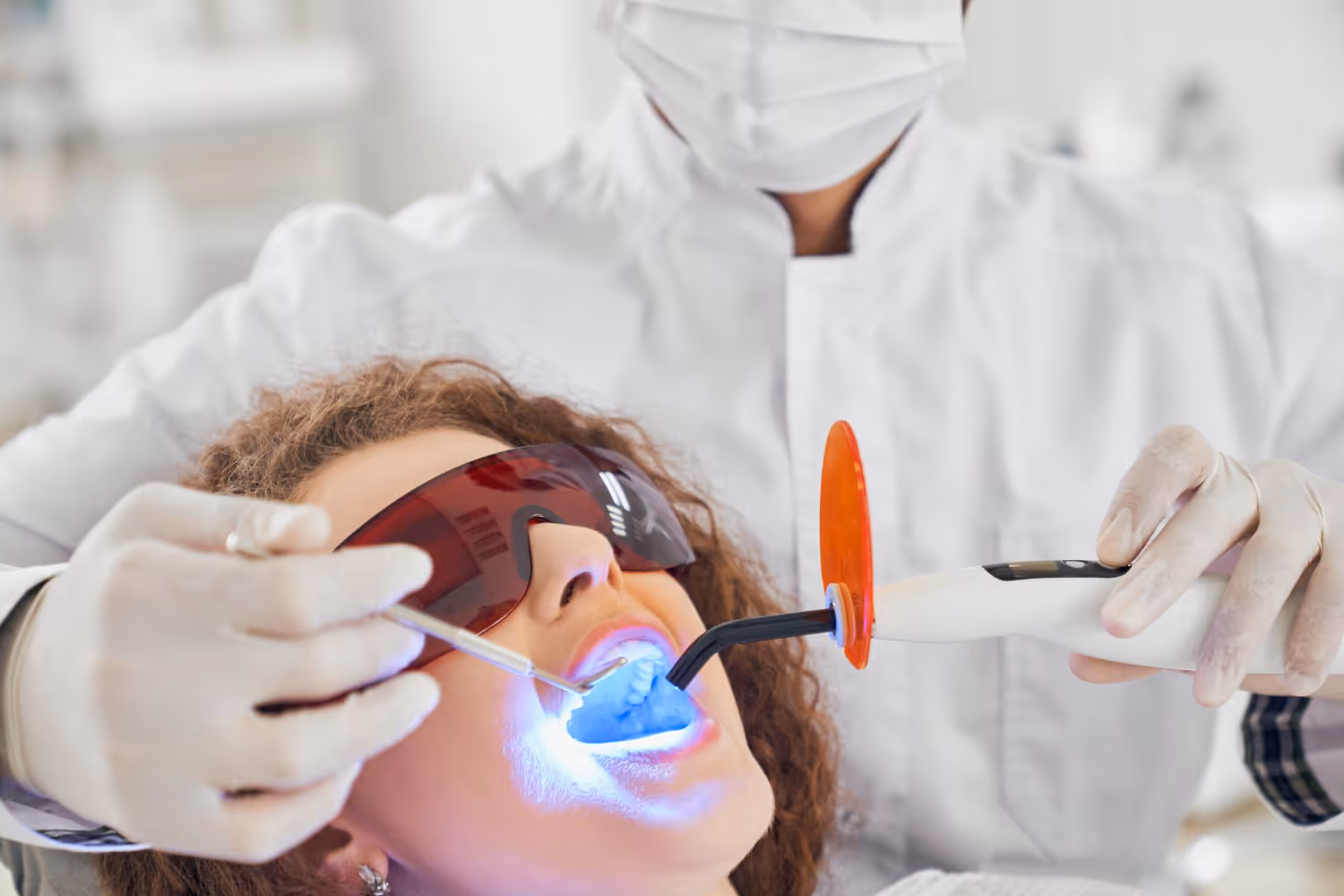 Patientin mit Schutzbrille erhält eine professionelle Zahnaufhellung mit LED-Licht bei Dübi Dental – modernes Bleaching für weissere Zähne in Dübendorf.