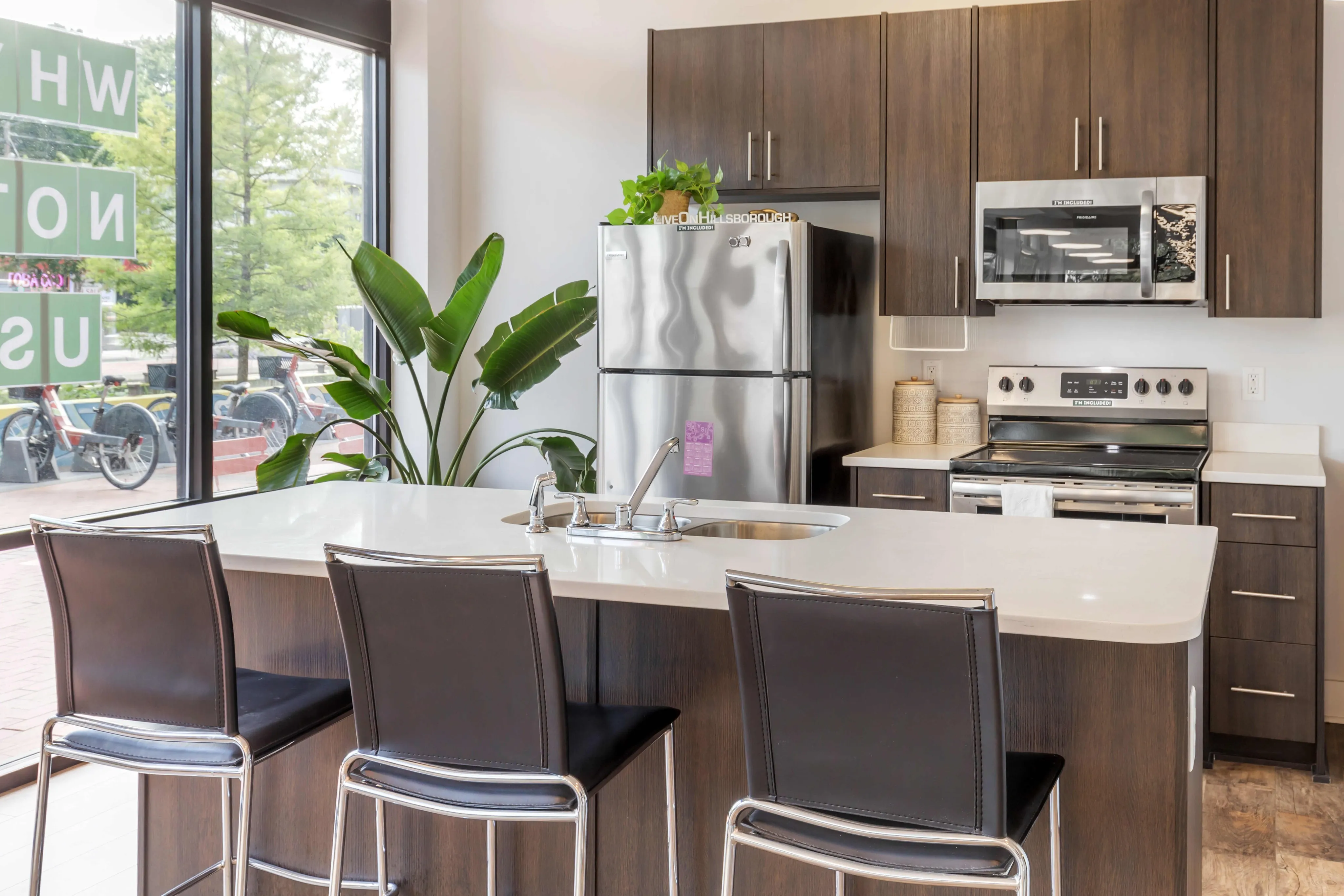 Kitchen with stainless steel appliances and bar with chairs